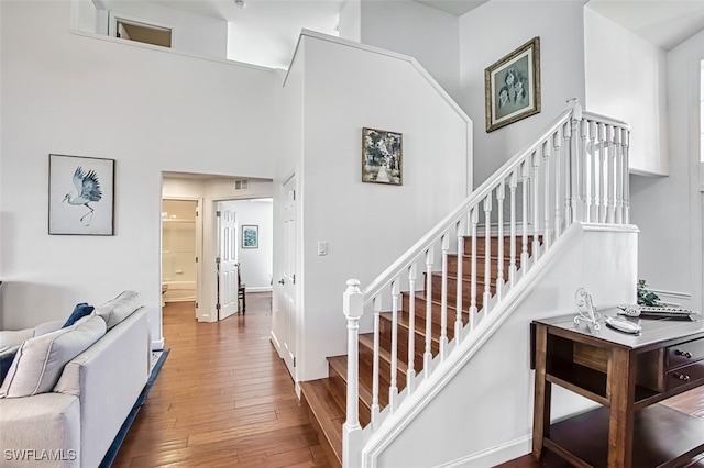 stairway featuring a high ceiling and hardwood / wood-style floors