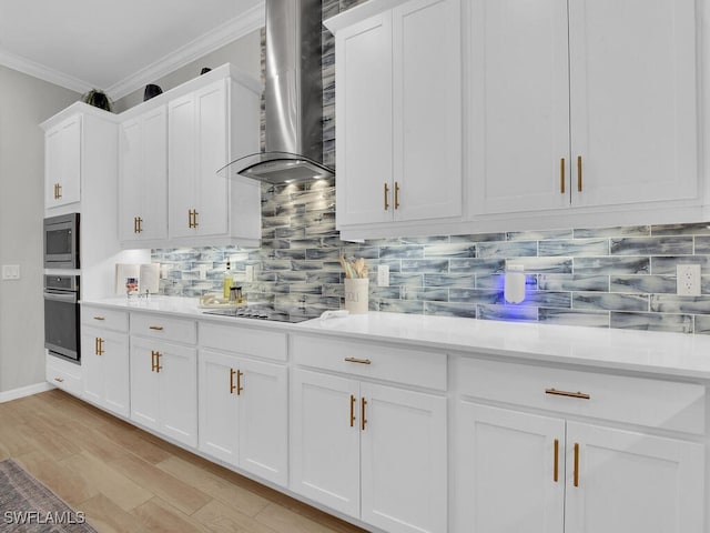 kitchen featuring white cabinetry, ornamental molding, stainless steel appliances, and wall chimney exhaust hood