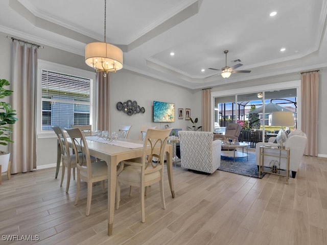 dining room featuring ornamental molding, a raised ceiling, and light wood-type flooring