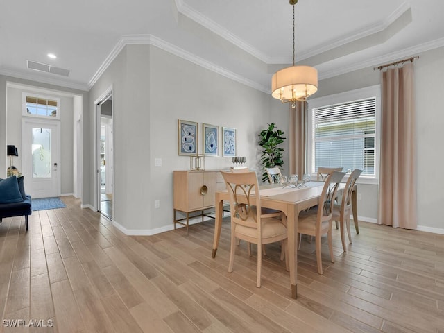 dining area featuring a raised ceiling, crown molding, and light hardwood / wood-style floors