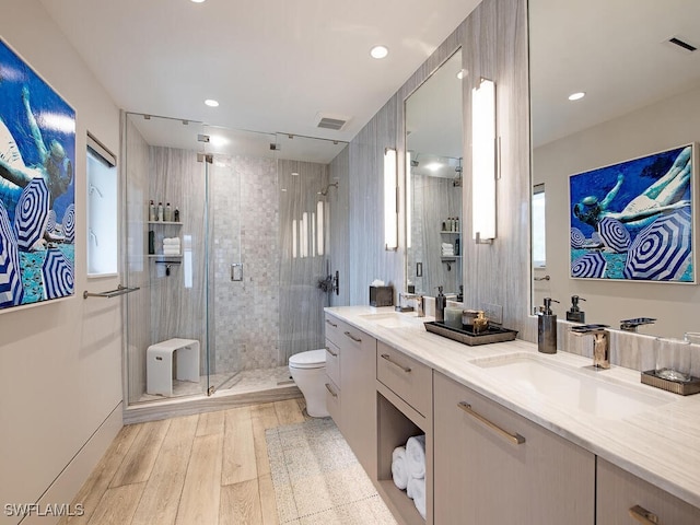 bathroom featuring toilet, wood-type flooring, vanity, a shower with door, and a healthy amount of sunlight