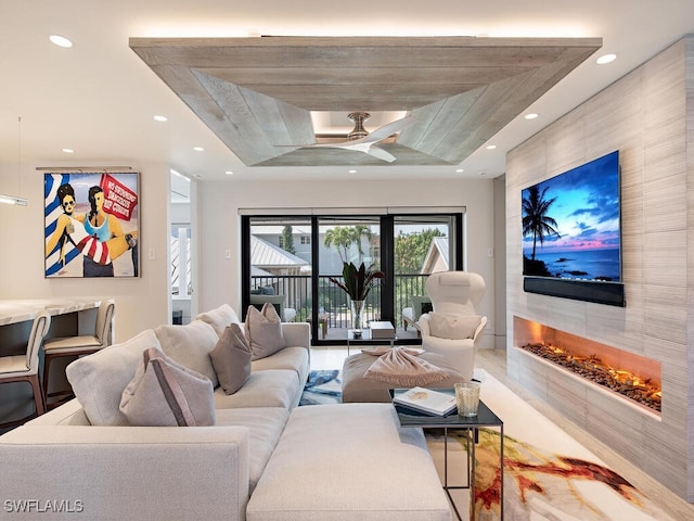 living room featuring a tile fireplace and ceiling fan