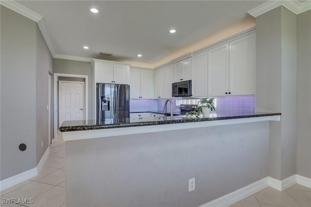 kitchen with light tile patterned flooring, dark stone countertops, kitchen peninsula, stainless steel appliances, and white cabinets