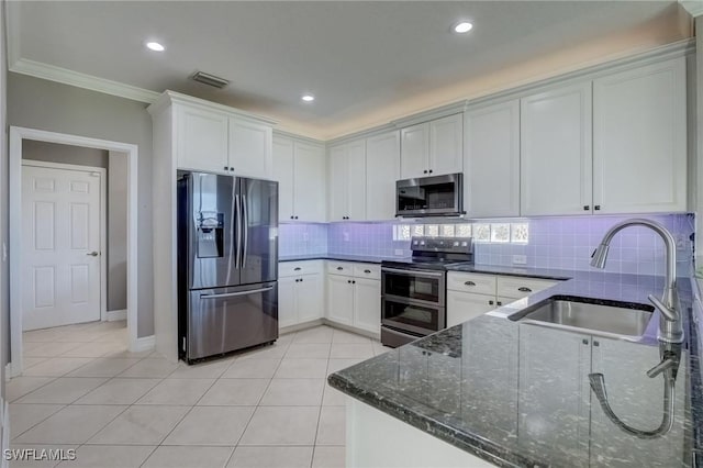 kitchen with light tile patterned flooring, sink, appliances with stainless steel finishes, dark stone counters, and white cabinets