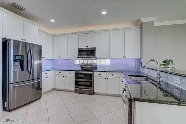 kitchen with tasteful backsplash, white cabinetry, sink, dark stone counters, and stainless steel appliances