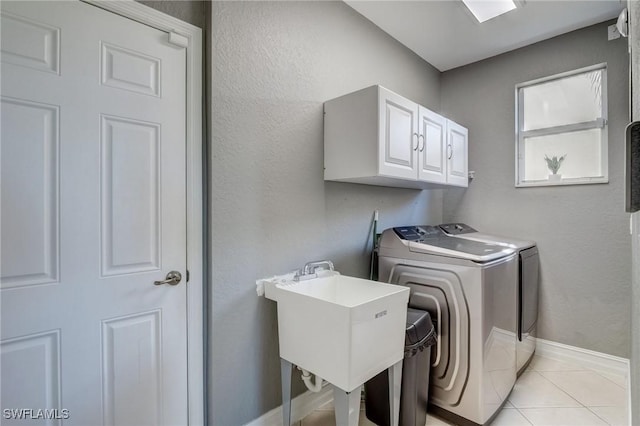 clothes washing area with cabinets, sink, light tile patterned floors, and independent washer and dryer