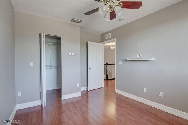 unfurnished bedroom with wood-type flooring, a closet, and ceiling fan