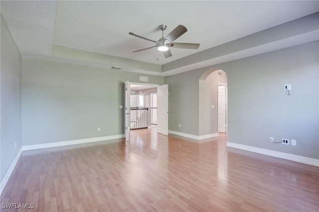 spare room featuring ceiling fan, a tray ceiling, and light wood-type flooring