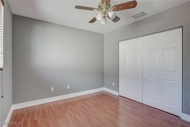 unfurnished bedroom with ceiling fan, light wood-type flooring, and a closet