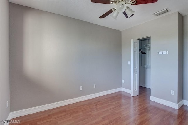 unfurnished bedroom featuring ceiling fan, wood-type flooring, a spacious closet, and a closet