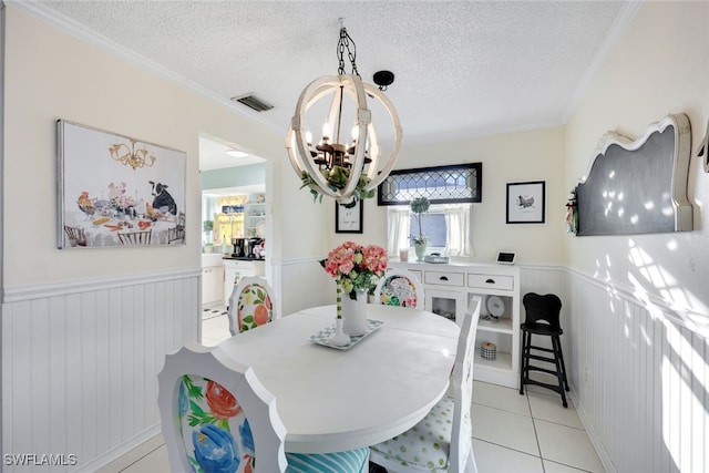 dining space with crown molding, a textured ceiling, a chandelier, and light tile patterned flooring