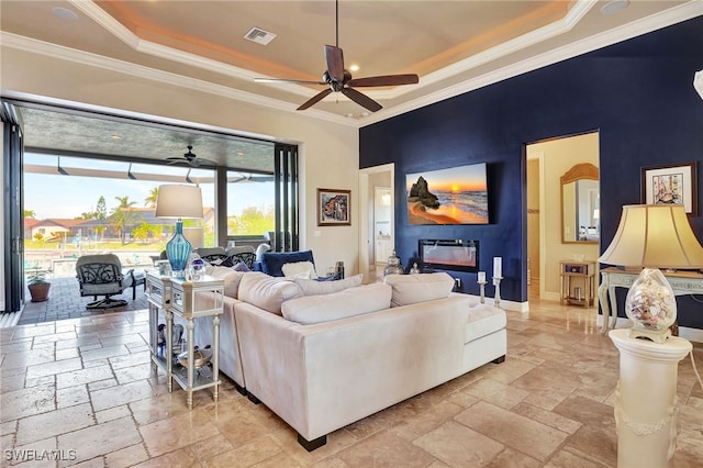 living room featuring ornamental molding, a fireplace, and a tray ceiling