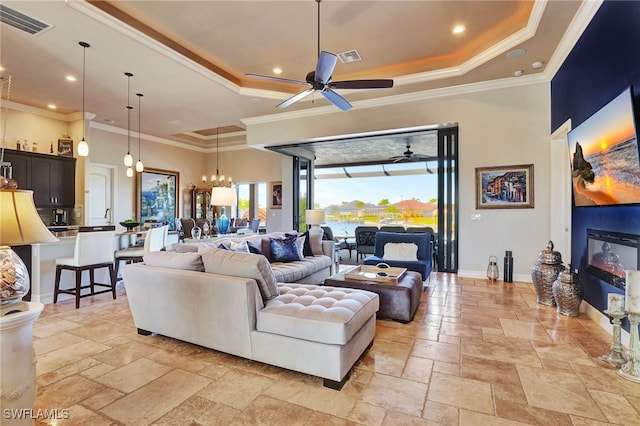 living room featuring crown molding, a healthy amount of sunlight, and a tray ceiling