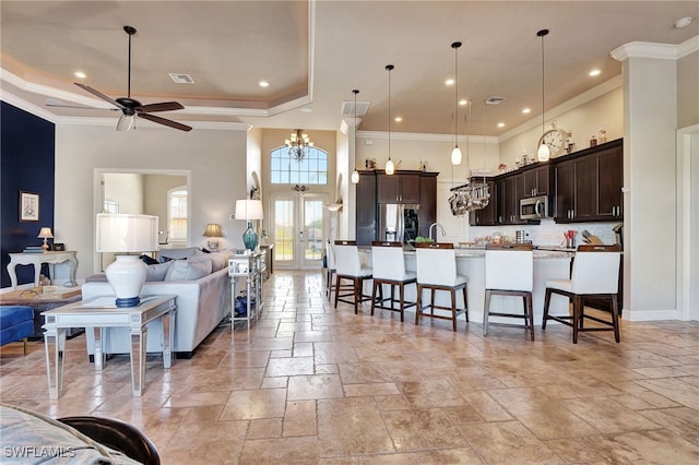 kitchen featuring a spacious island, decorative light fixtures, appliances with stainless steel finishes, a kitchen breakfast bar, and a raised ceiling