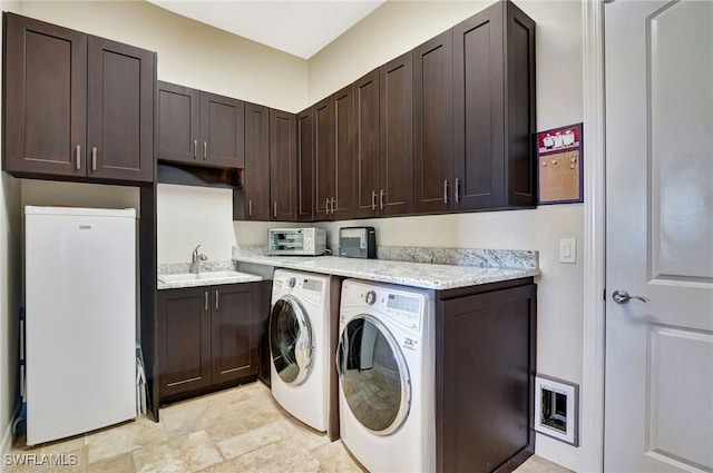 laundry area featuring cabinets, separate washer and dryer, and sink