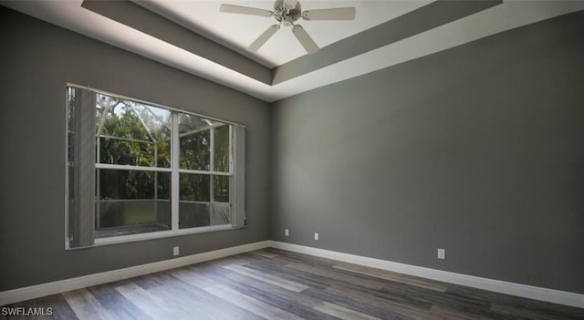 spare room with hardwood / wood-style flooring, ceiling fan, and a raised ceiling