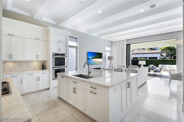 kitchen featuring sink, light stone counters, white cabinets, and double oven