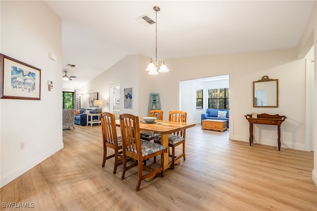 dining space with a healthy amount of sunlight, high vaulted ceiling, light hardwood / wood-style flooring, and a notable chandelier