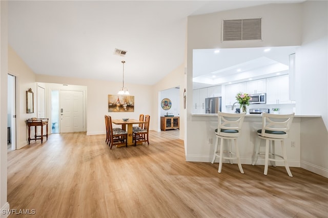 kitchen with white cabinetry, a kitchen breakfast bar, kitchen peninsula, stainless steel appliances, and light wood-type flooring