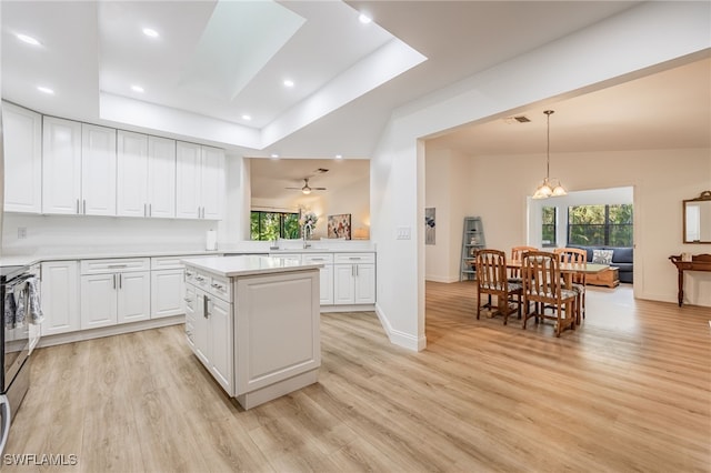 kitchen with white cabinetry, a tray ceiling, light wood-type flooring, and pendant lighting