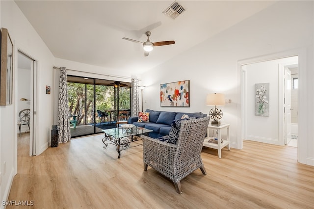 living room with ceiling fan, vaulted ceiling, and light wood-type flooring