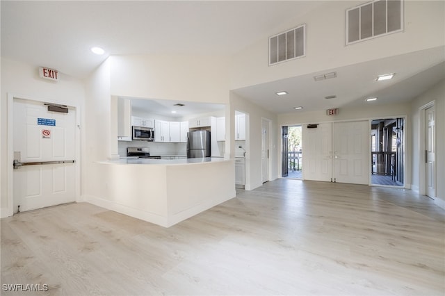 kitchen featuring white cabinetry, stainless steel appliances, kitchen peninsula, and light wood-type flooring