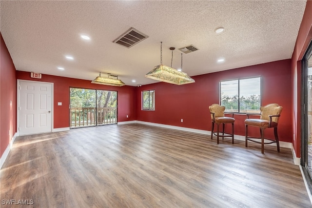 living area with hardwood / wood-style flooring, a wealth of natural light, and a textured ceiling