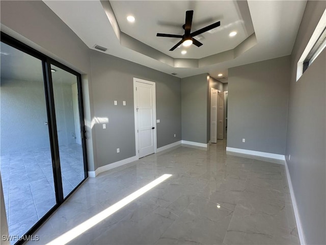 unfurnished bedroom featuring a tray ceiling and ceiling fan