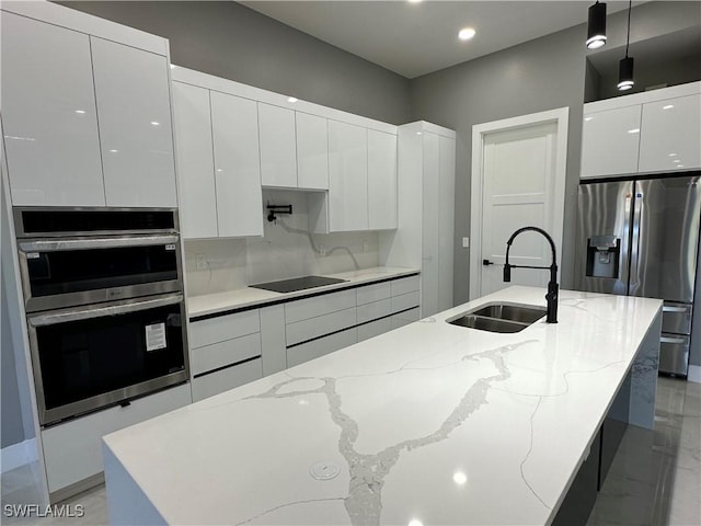 kitchen featuring hanging light fixtures, stainless steel appliances, sink, and a center island with sink