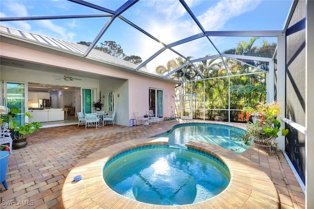 view of swimming pool featuring a patio area, an in ground hot tub, ceiling fan, and glass enclosure