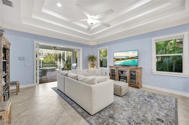 tiled living room featuring ceiling fan and a tray ceiling