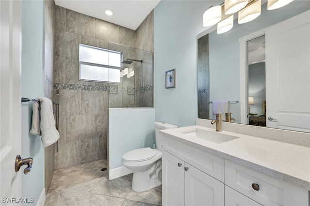 bathroom with vanity, a tile shower, and toilet