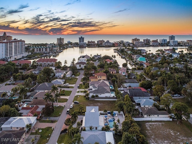 aerial view at dusk featuring a water view