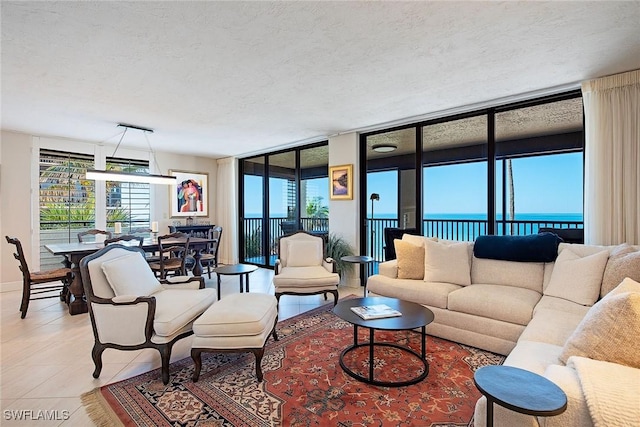 living room featuring a wall of windows, a textured ceiling, and a water view