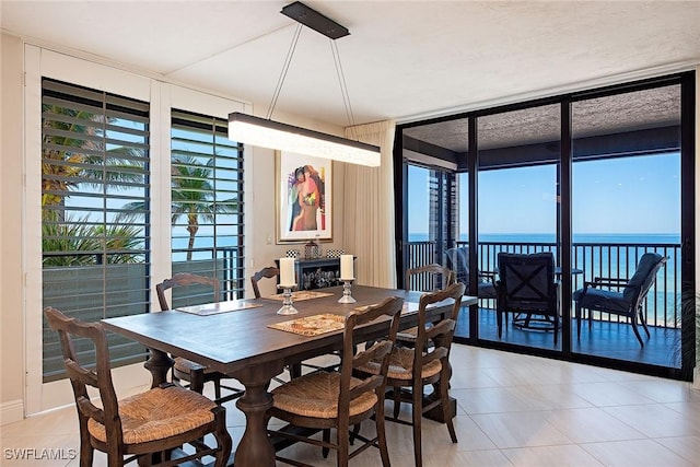 tiled dining room with plenty of natural light, expansive windows, and a water view