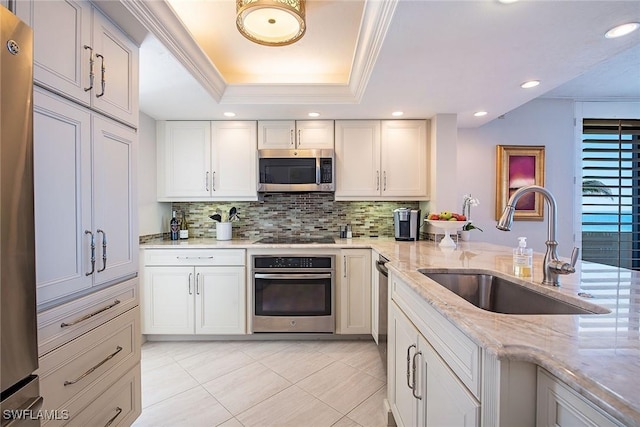 kitchen with a raised ceiling, white cabinetry, appliances with stainless steel finishes, and sink