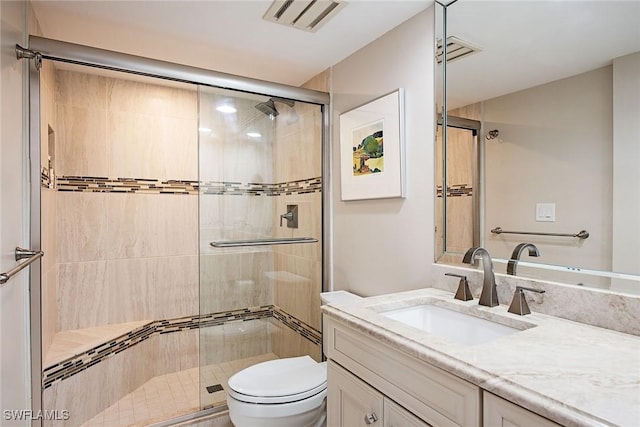 bathroom featuring vanity, a shower with shower door, and toilet