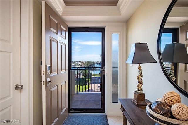 doorway with crown molding, light tile patterned floors, and a tray ceiling