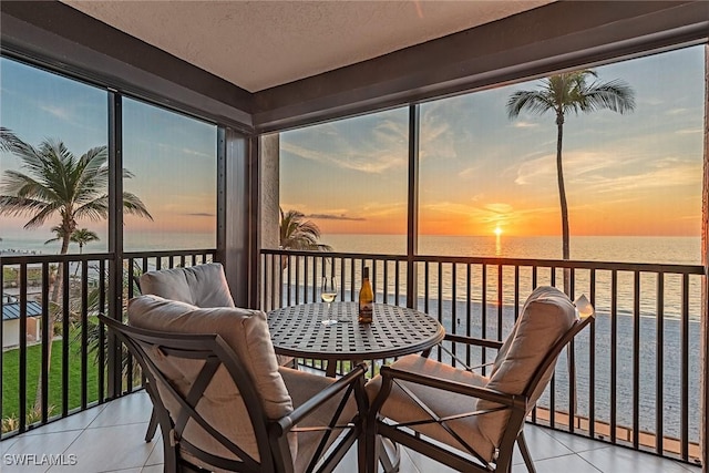 sunroom with a water view and a view of the beach