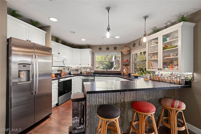 kitchen with a breakfast bar area, white cabinets, hanging light fixtures, kitchen peninsula, and stainless steel appliances