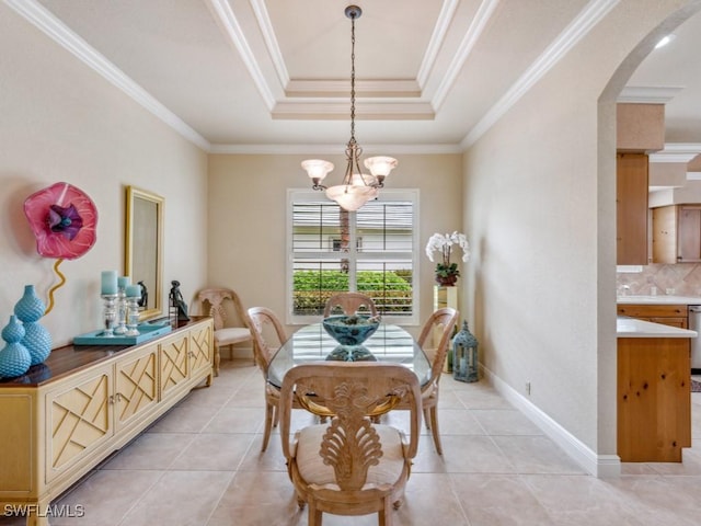 dining room with an inviting chandelier, ornamental molding, a raised ceiling, and light tile patterned floors