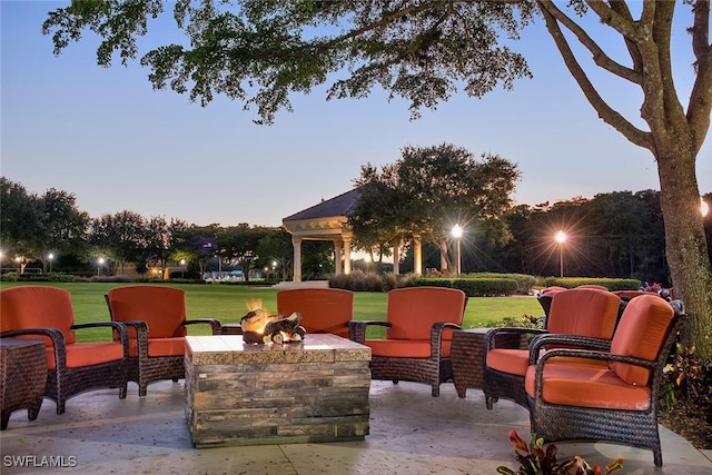 patio terrace at dusk with a lawn and an outdoor living space with a fire pit