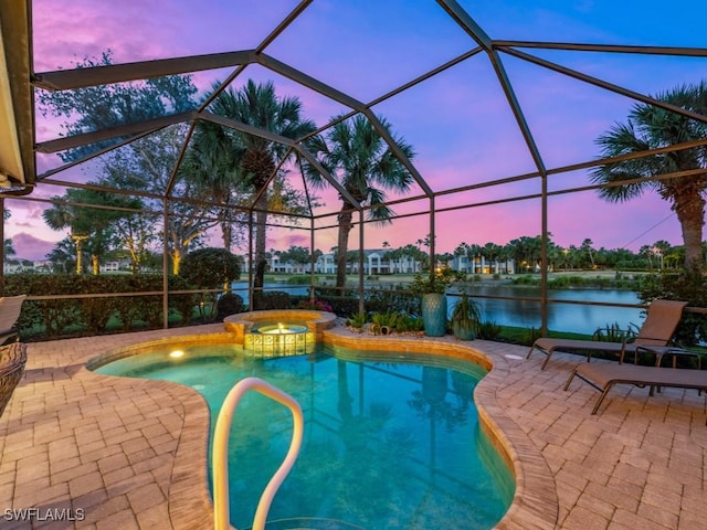 pool at dusk featuring a patio, a lanai, a water view, and an in ground hot tub