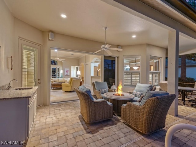 view of patio featuring sink, an outdoor living space with a fire pit, and ceiling fan