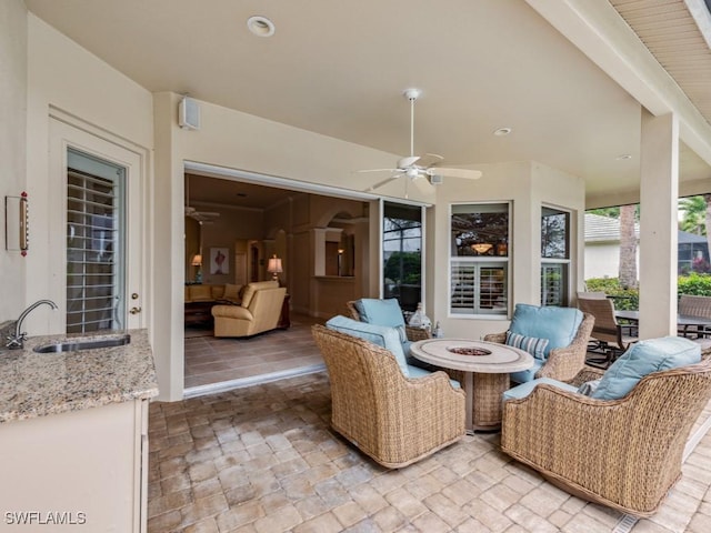 view of patio with sink, an outdoor living space with a fire pit, and ceiling fan