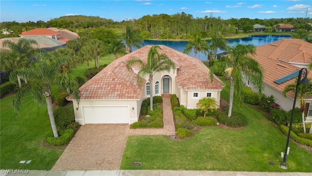 view of front of property featuring decorative driveway, stucco siding, a water view, an attached garage, and a front yard