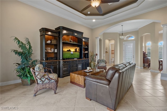 tiled living room featuring ornate columns, ornamental molding, ceiling fan, and a tray ceiling