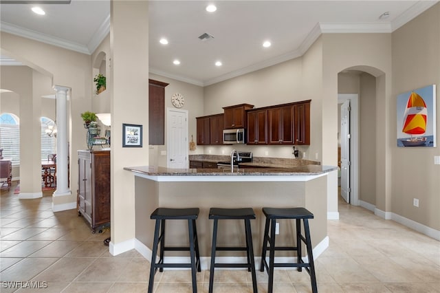 kitchen featuring crown molding, stainless steel appliances, decorative columns, light tile patterned flooring, and kitchen peninsula