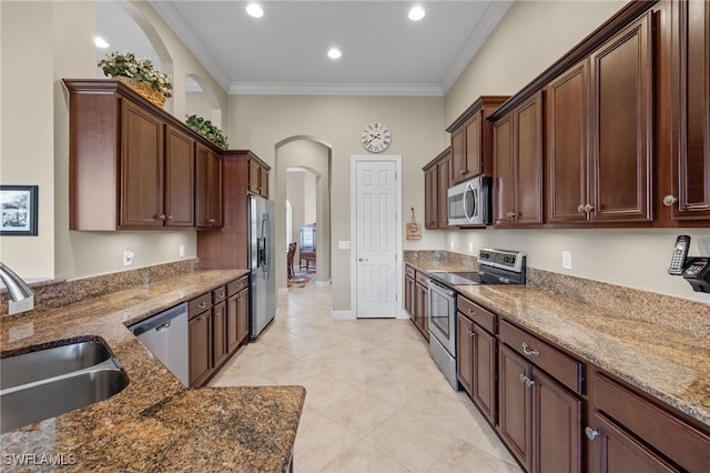 kitchen featuring sink, dark brown cabinets, stainless steel appliances, ornamental molding, and dark stone counters