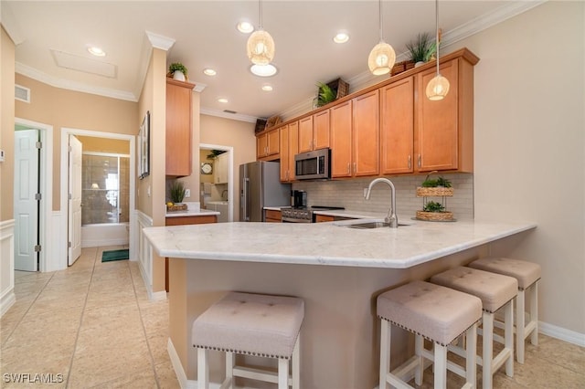 kitchen with sink, a breakfast bar area, appliances with stainless steel finishes, kitchen peninsula, and pendant lighting